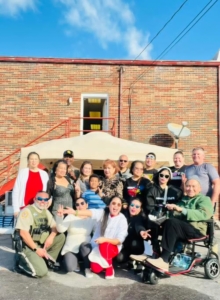 A group of volunteers gather in front of a tent for a group picture.
