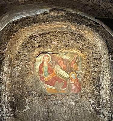 image shows a cave wall with carved art of the nativity.