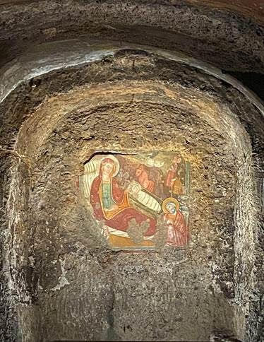 image shows a cave wall with carved art of the nativity.